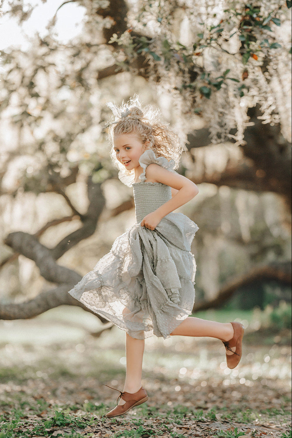 Girl walking through the orchard in the Bay Leaf Orchard Collection dress with a flowing tiered silhouette.