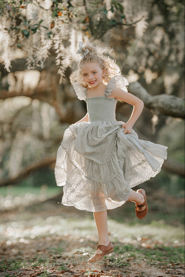 Girl twirling in the Bay Leaf Orchard Collection dress designed with flutter sleeves and a tiered heirloom skirt.