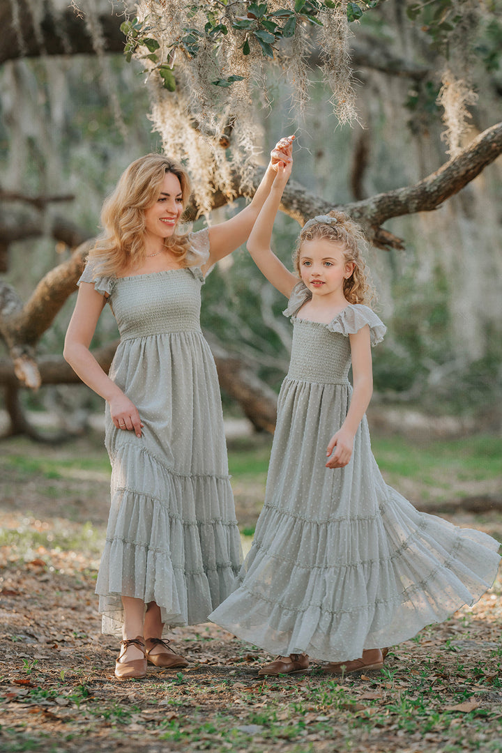 Mother and daughter wearing matching Bay Leaf Orchard Collection dresses in soft sage green Swiss dot fabric.
