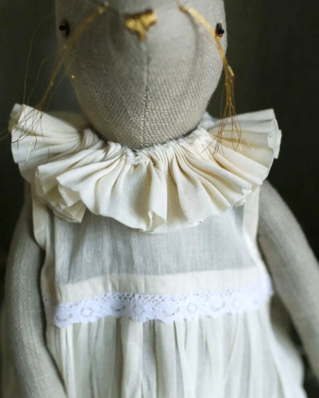 Close-up detail of the pleated ruffle collar and cotton dress on a handcrafted bunny art doll