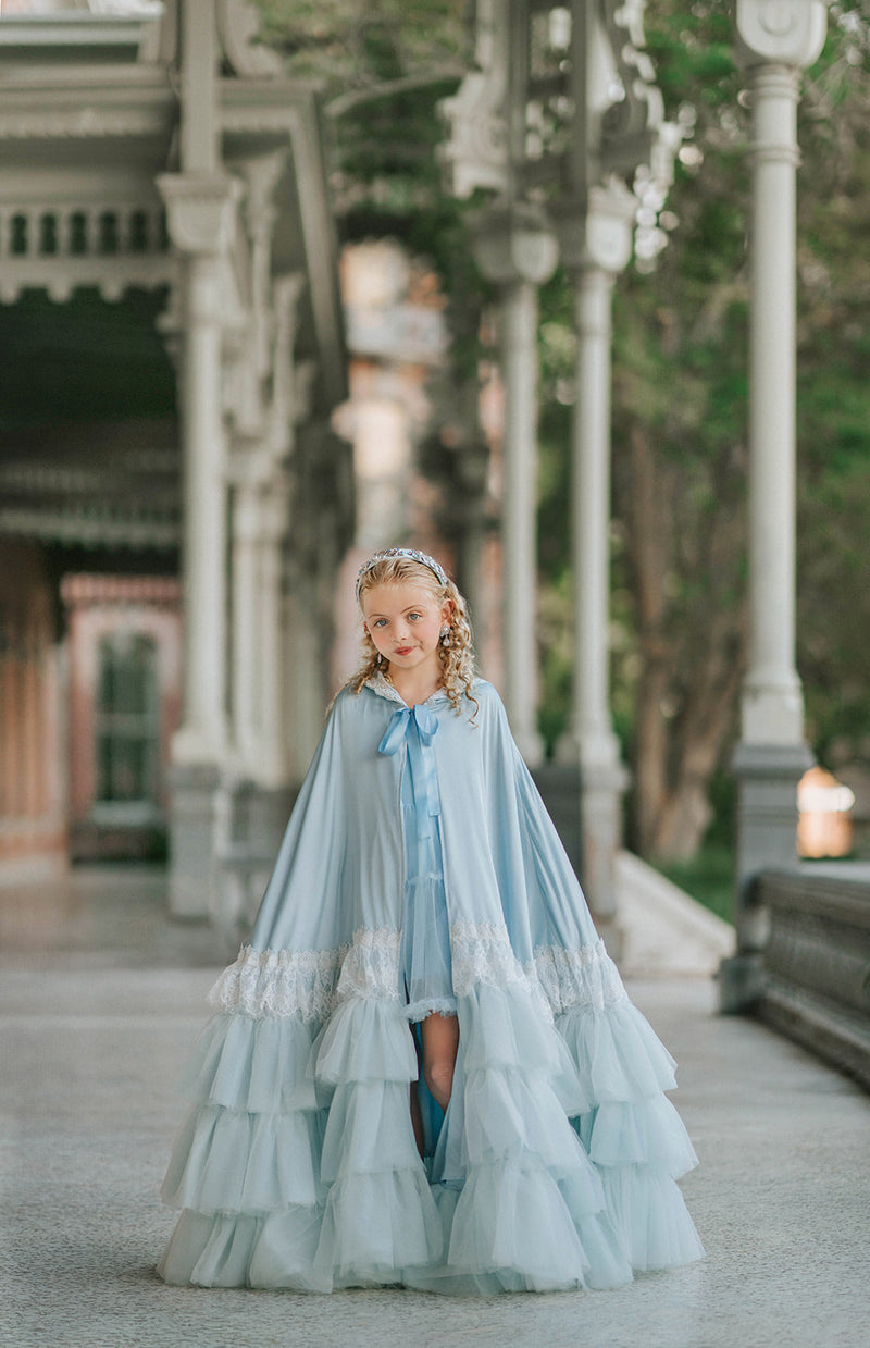 Full-length view of The Cendrillon pale blue princess cape with satin ribbon tie, white lace trim and tiered tulle ruffles