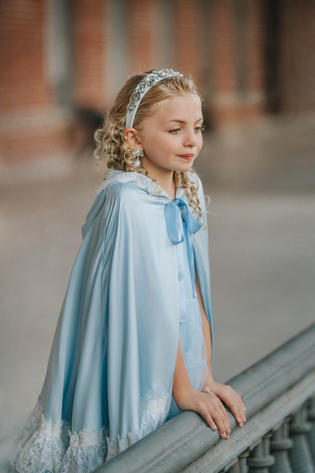 Detail of The Cendrillon blue satin princess cape showing white lace trim, gathered neckline and pale blue ribbon tie