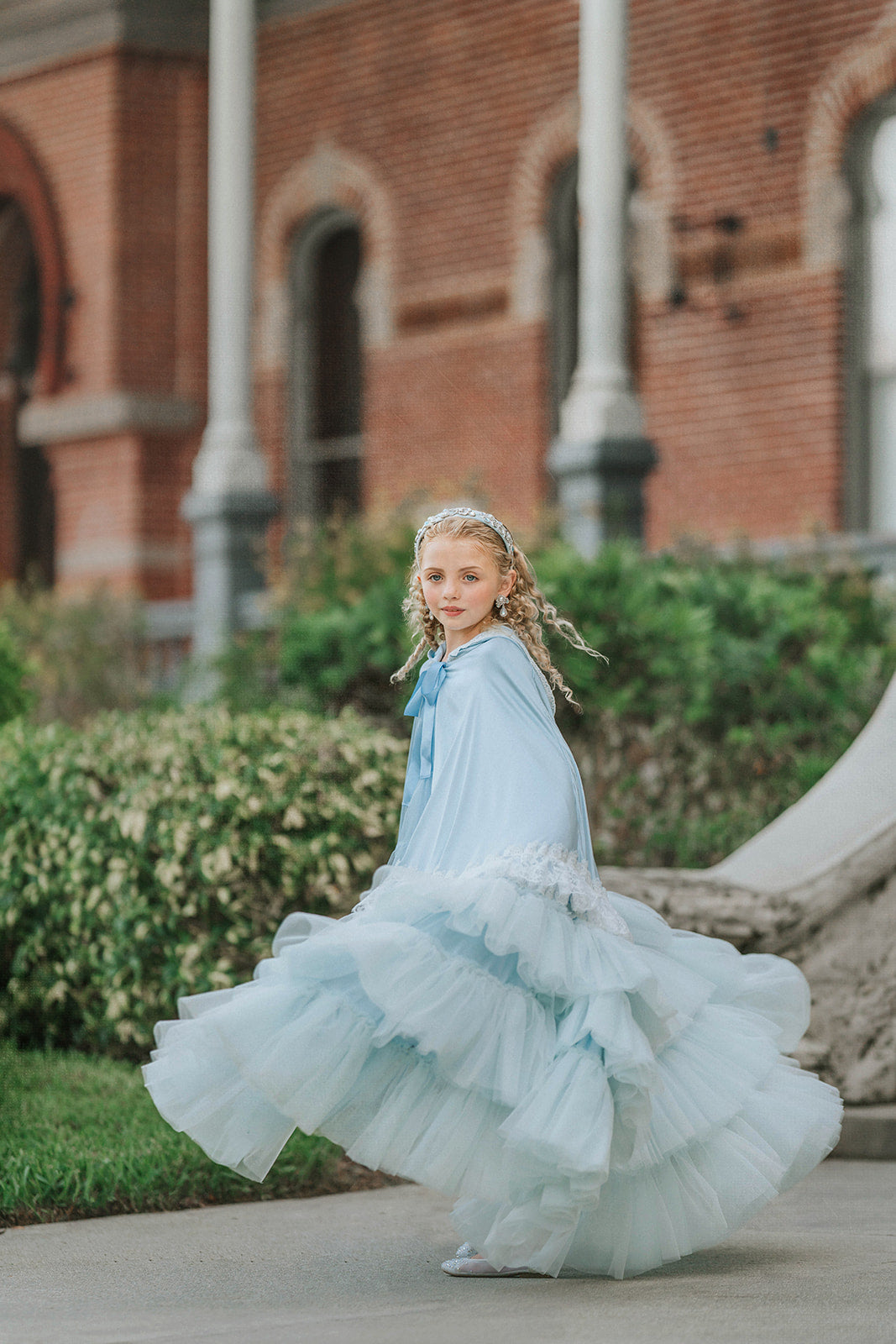 Side view of The Cendrillon pale blue satin cape with delicate white lace trim and coordinating satin ribbon tie twirling