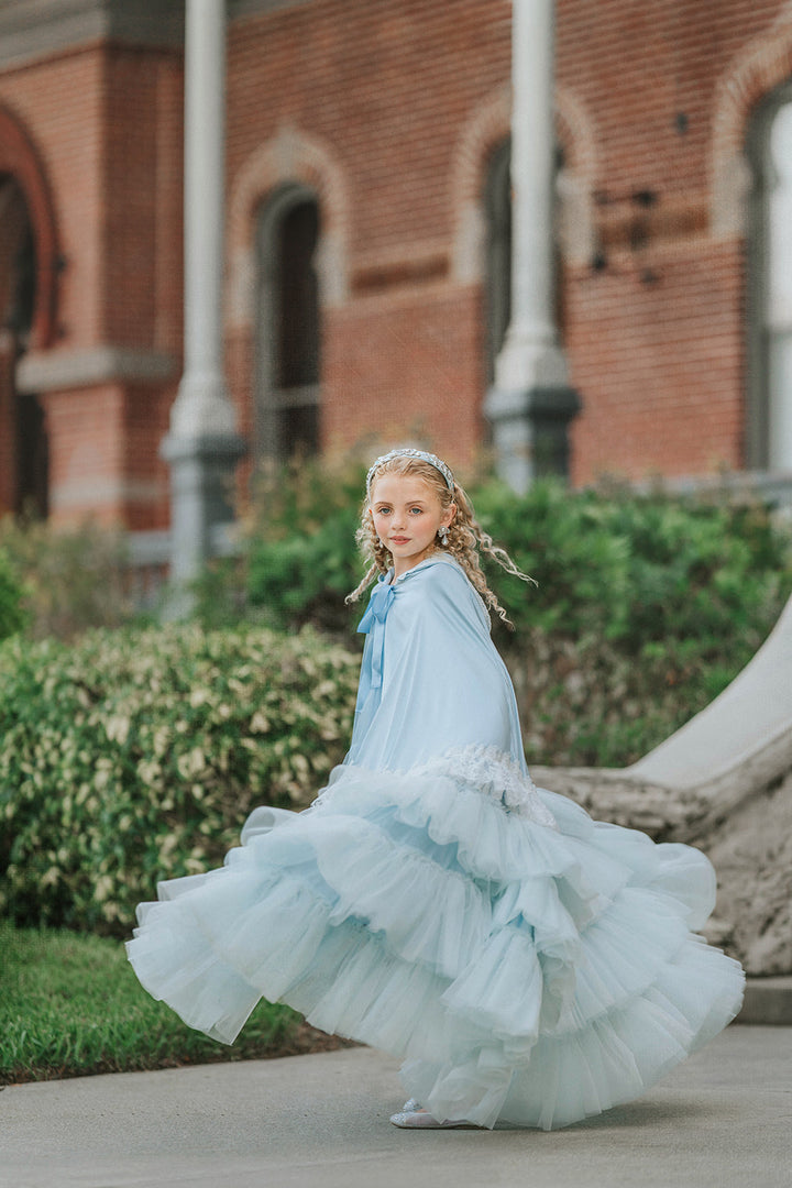 Side view of The Cendrillon pale blue satin cape with delicate white lace trim and coordinating satin ribbon tie twirling
