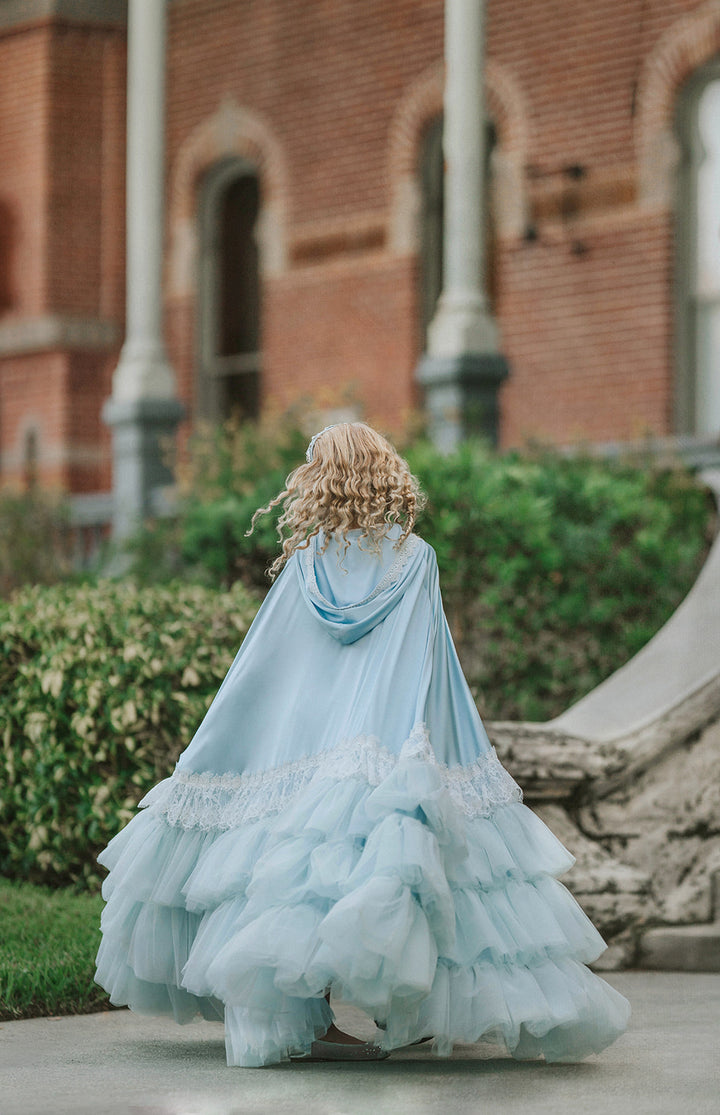 Backview of a Cinderella-inspired blue princess cape with white lace detailing and dramatic tiered tulle ruffles