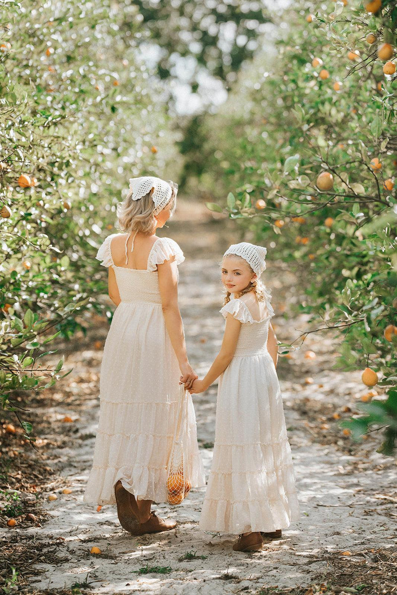 Mother and daughter wearing matching Citrus Cream Swiss dot dresses from the Orchard Collection