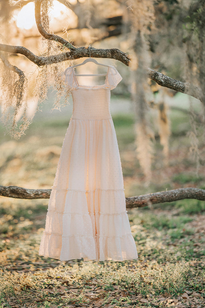 Citrus Cream Swiss dot maxi dress hanging beneath oak branches showing the full silhouette