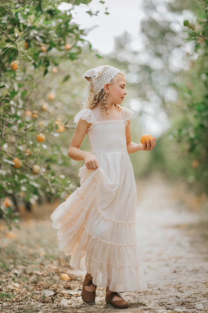 Girl twirling in the Citrus Cream Orchard Dress showcasing the flowing full skirt and soft Swiss dot fabric