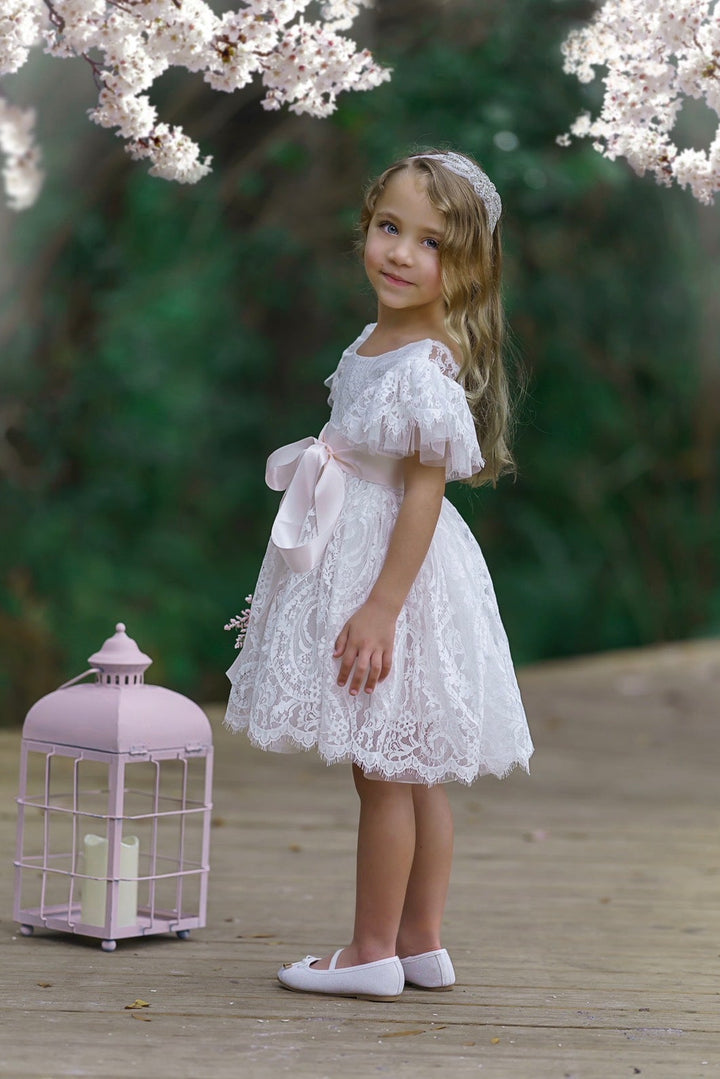 Side view of soft white lace flower girl dress with ruffle sleeves and tied satin bow sash, classic bridal party dress.