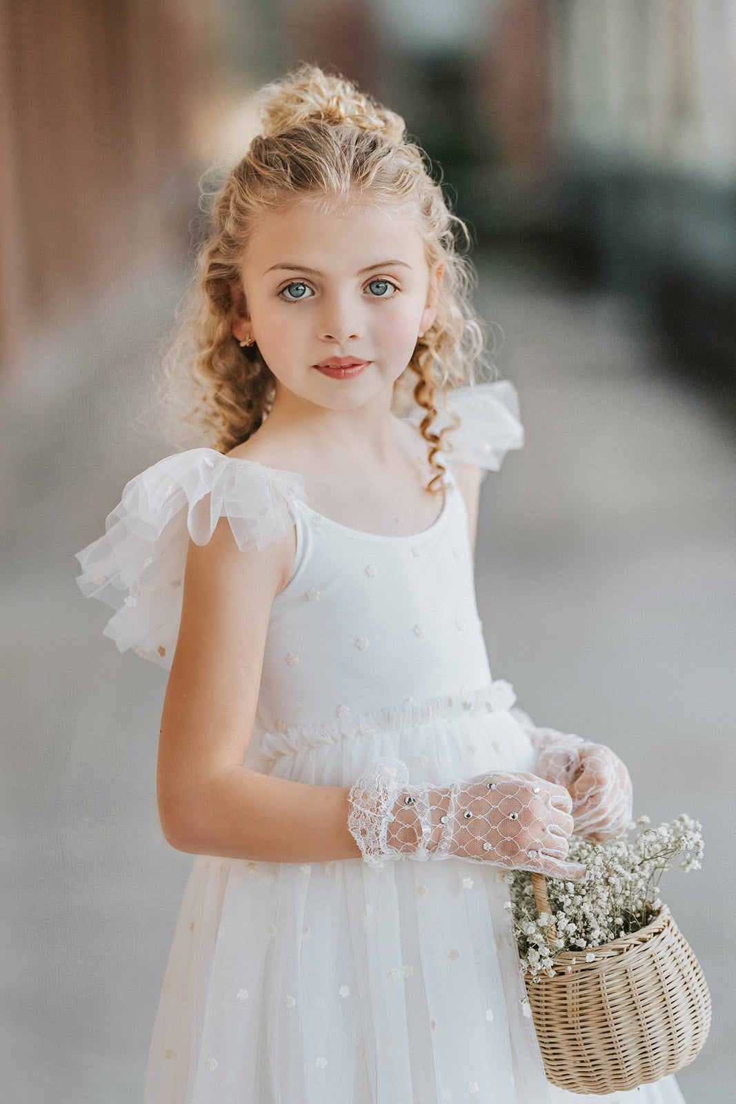 Close up of soft white embroidered floral tulle flower girl dress bodice with delicate ruffle sleeves, heirloom wedding dress detail