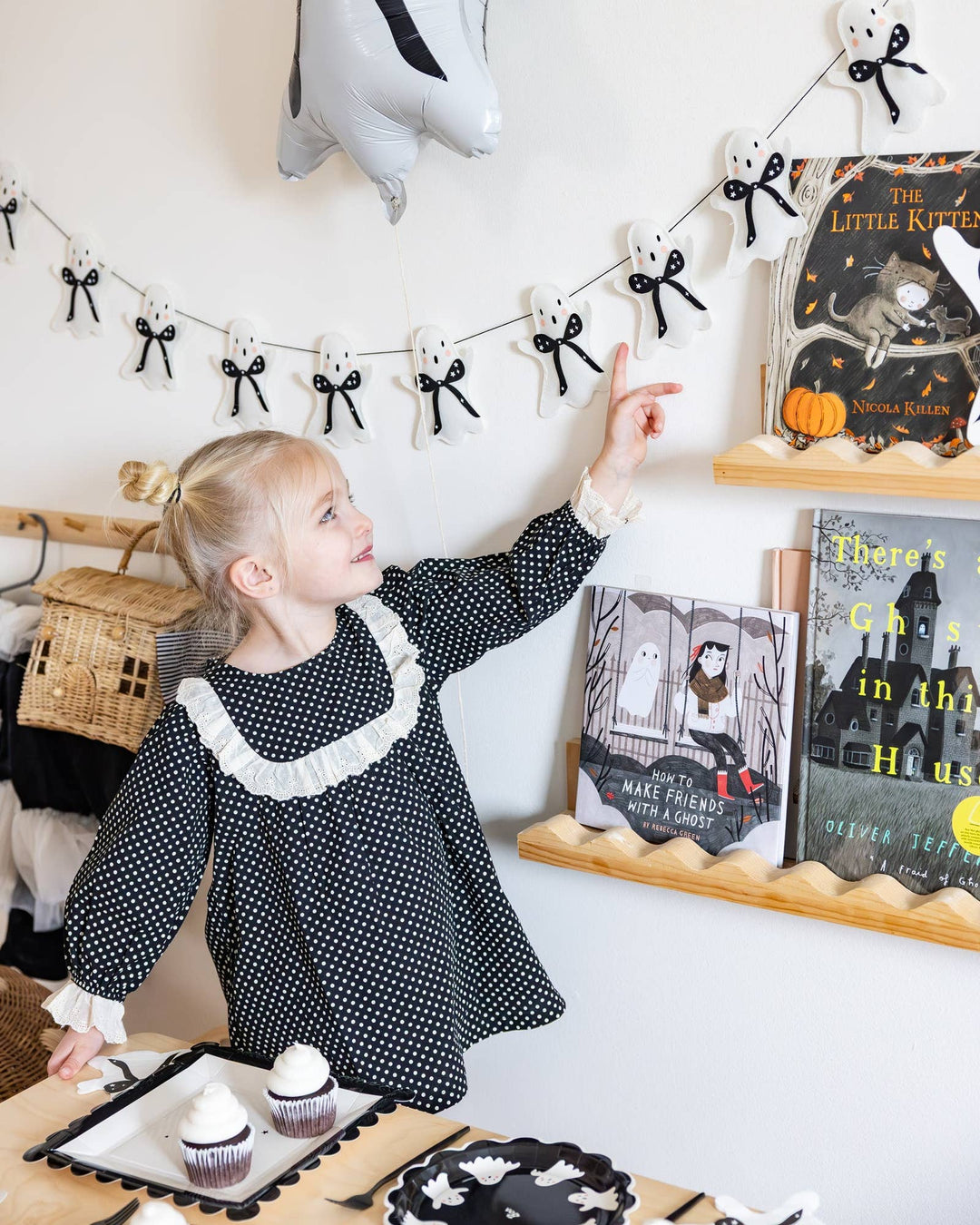 My Mind’s Eye felt ghost Halloween garland displayed on the wall as a little girl prepares a Halloween party