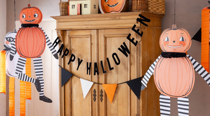 Vintage Halloween felt pennant banner displayed above a festive table setting with pumpkins, treats and seasonal decorations