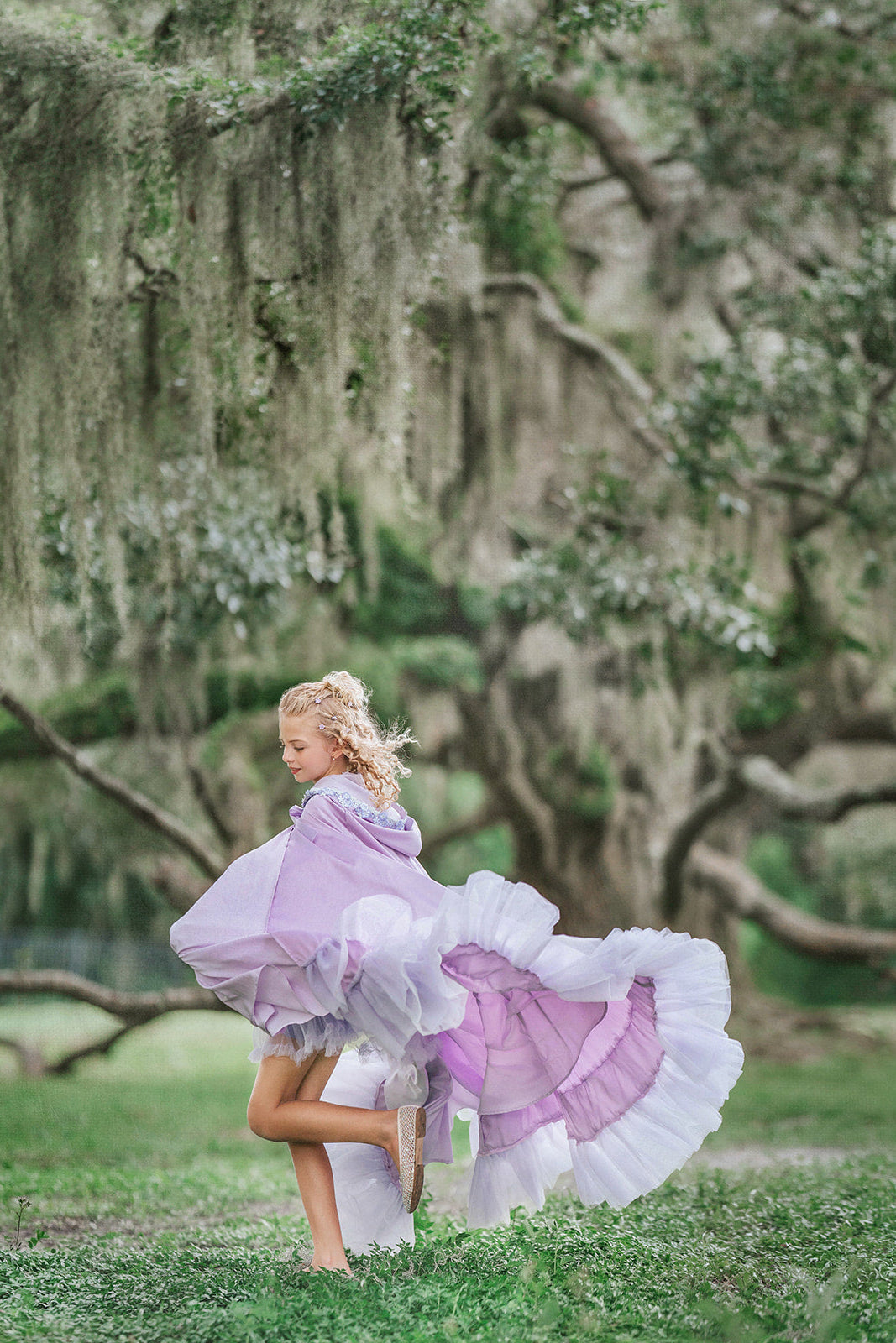 Girl wearing hooded lavender satin princess cape with layered tulle ruffle trim in an enchanted woodland setting