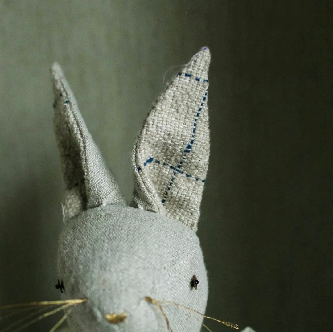 Close-up of hand-stitched facial details on a linen bunny ragdoll