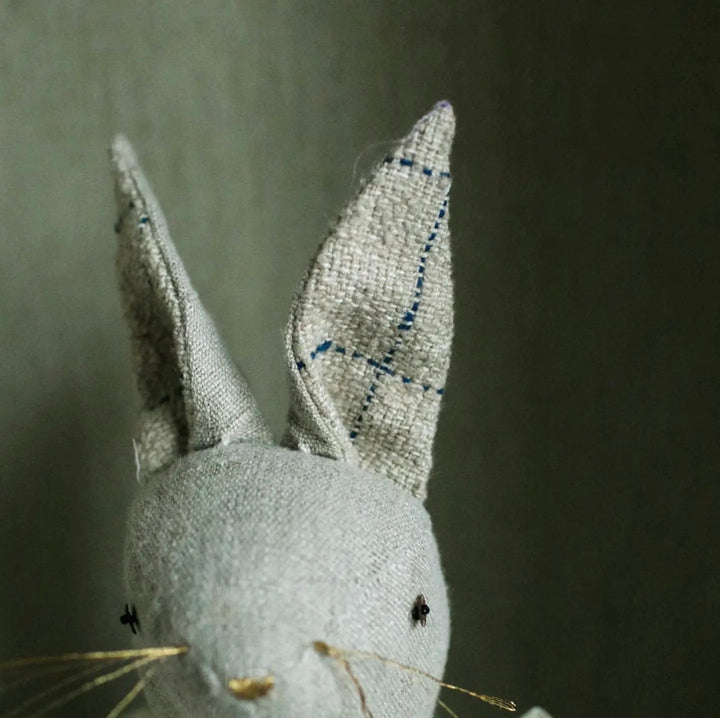 Close-up of hand-stitched facial details on a linen bunny ragdoll