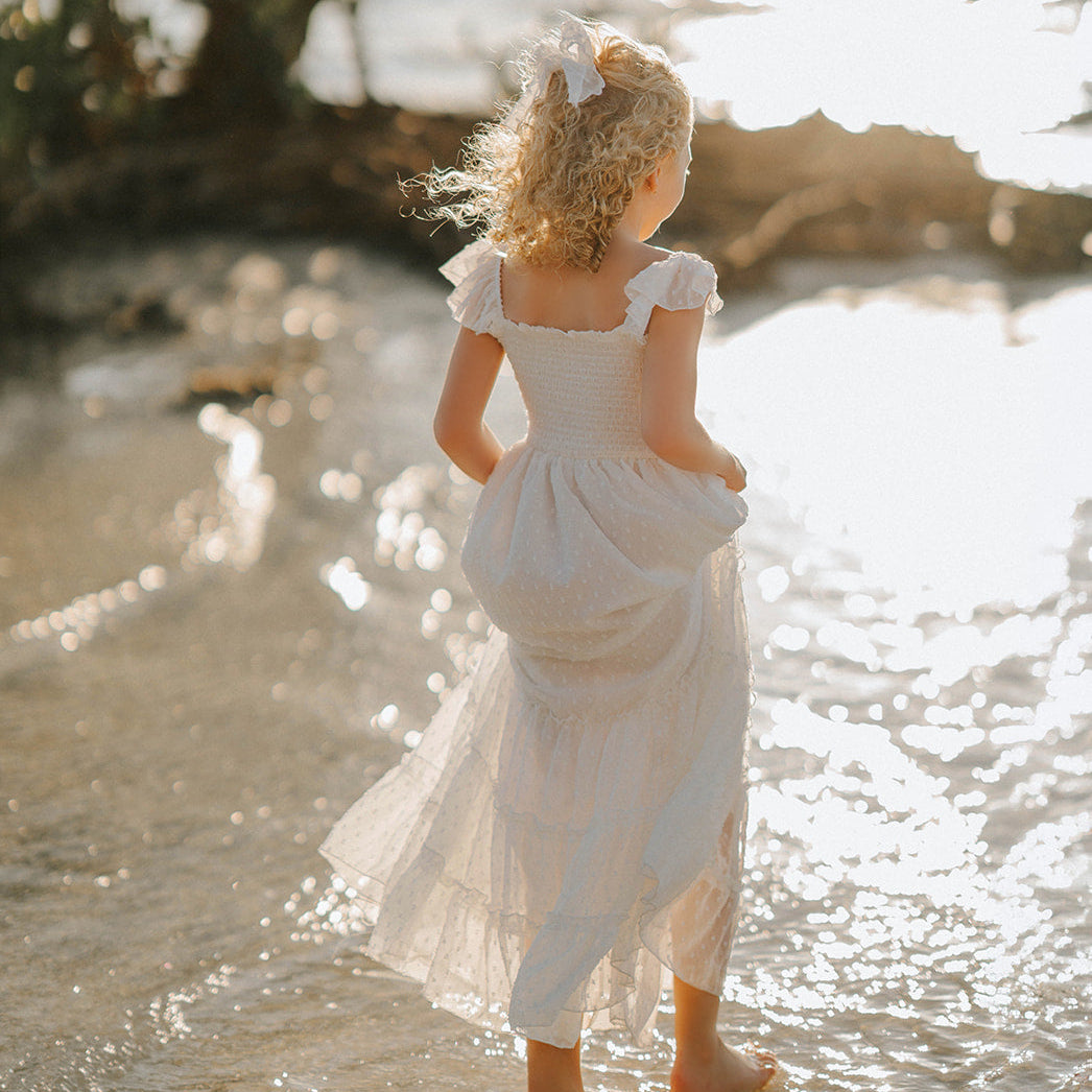 Girl wearing the Orange Blossom Orchard Collection dress during golden hour with soft sunlight illuminating the dress.
