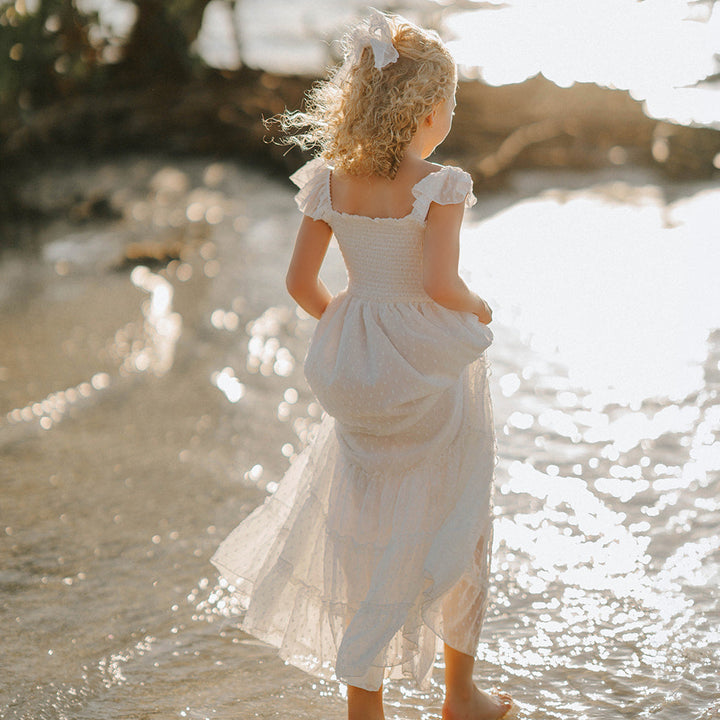 Girl wearing the Orange Blossom Orchard Collection dress during golden hour with soft sunlight illuminating the dress.