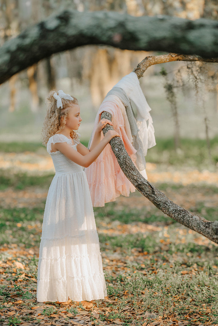 Side profile of a girl wearing the Orange Blossom Orchard Collection dress in soft white Swiss dot fabric.