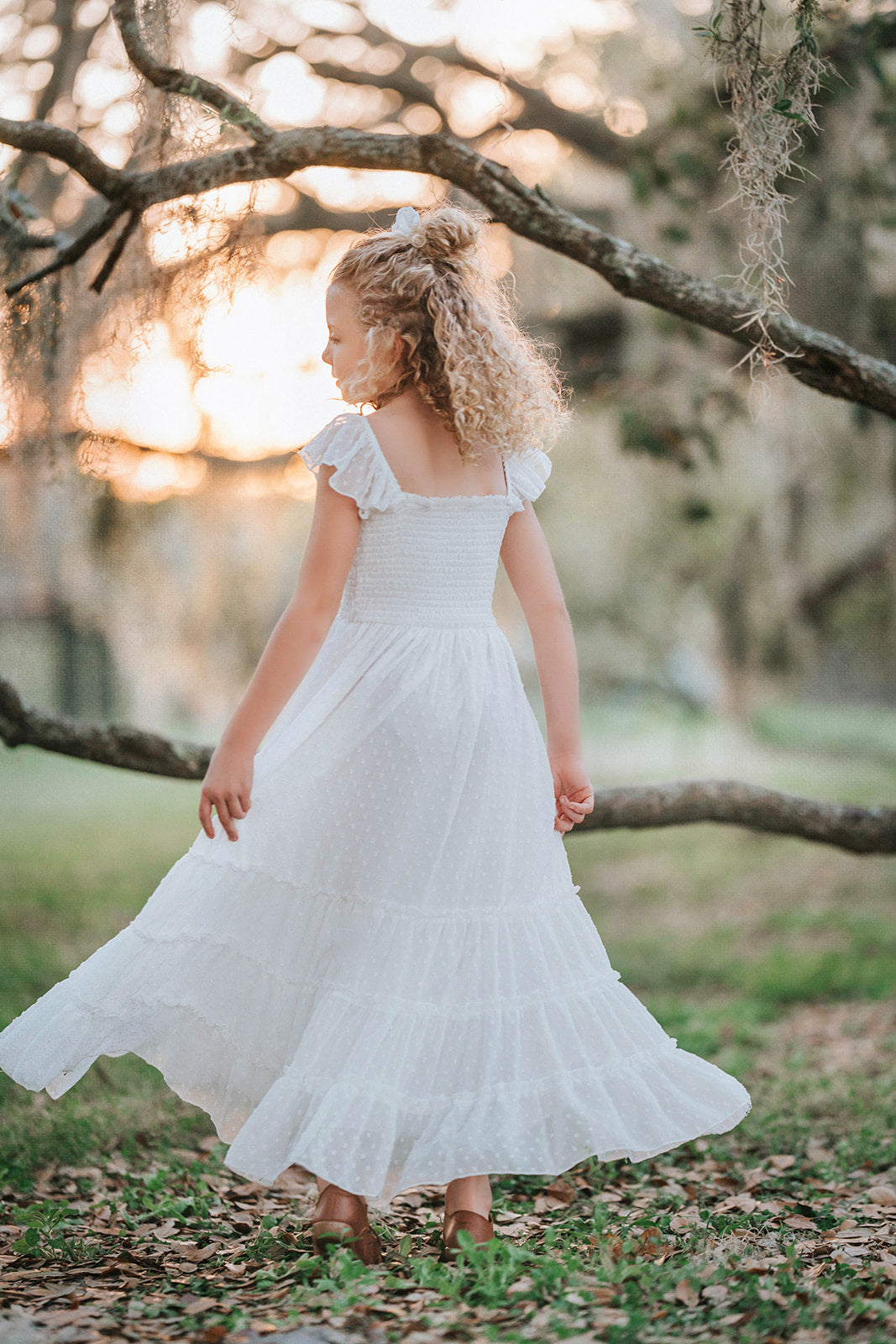 Girl twirling in the Orange Blossom Orchard Collection dress featuring a smocked bodice and tiered heirloom skirt.