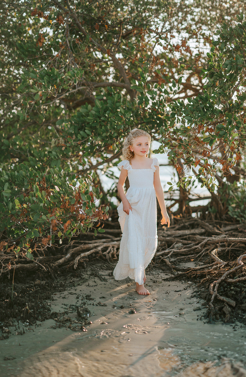 Girl standing barefoot in water wearing the Orange Blossom Orchard Collection dress in soft white Swiss dot fabric.