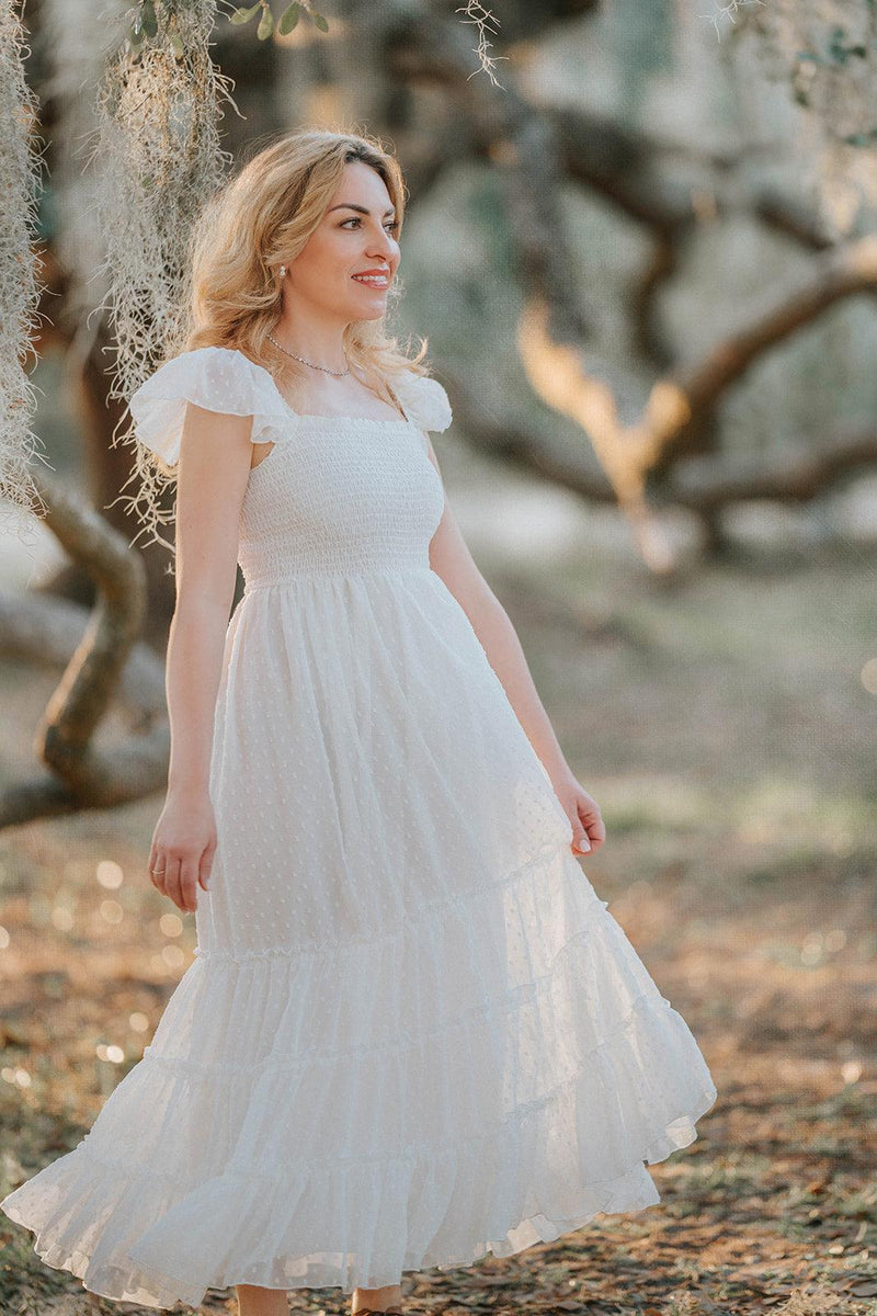 Woman wearing the Orange Blossom soft white Swiss dot maxi dress from the Orchard Collection by Autumn Moon.