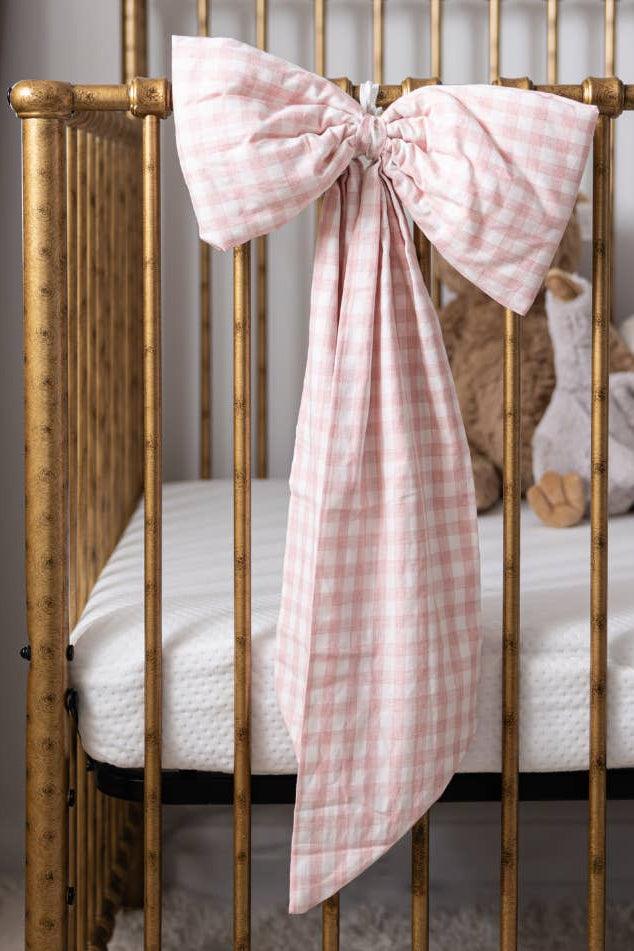 Large pink gingham crib bow styled on a nursery crib for timeless heirloom decor.