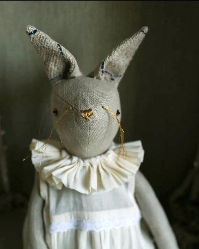 Front view of handcrafted rabbit ragdoll featuring a gathered cotton dress and artisan details
