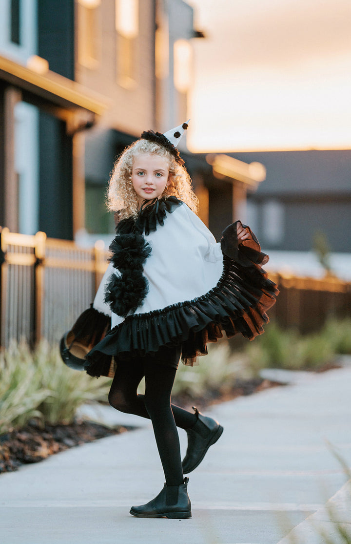 White satin Pirouette clown cape in motion showing its sweeping shape, contrasting black tulle trim and pom-pom details.