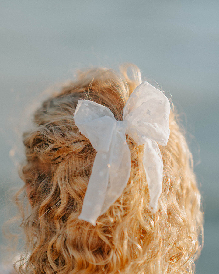 Close-up of Wild Strawberry Swiss dot boutique hair bow with soft flowing tails
