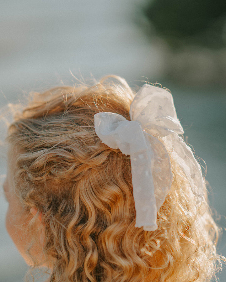 Girl wearing  Swiss dot hair bow coordinated with the Orchard Collection dress