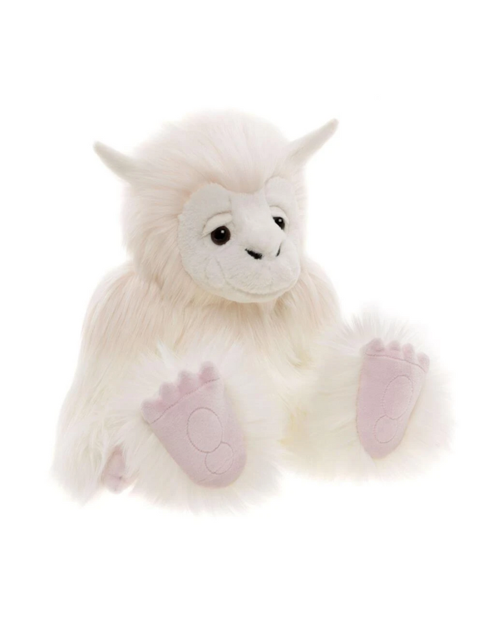 Tip Toe yeti stuffed animal seated at an angle, showing fluffy cream fur, two small white horns and oversized pink paws
