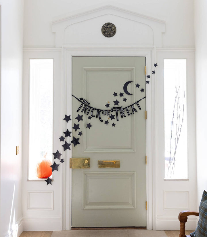 Felt Trick or Treat banner displayed across a front door with pumpkins and Halloween decorations