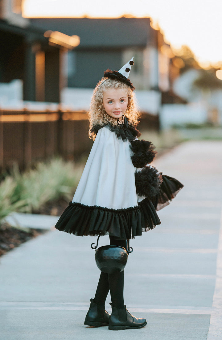 Side view of the white satin Pirouette clown cape showing the flowing satin silhouette, black tulle ruffles and pointed hat.

Cape in Motion