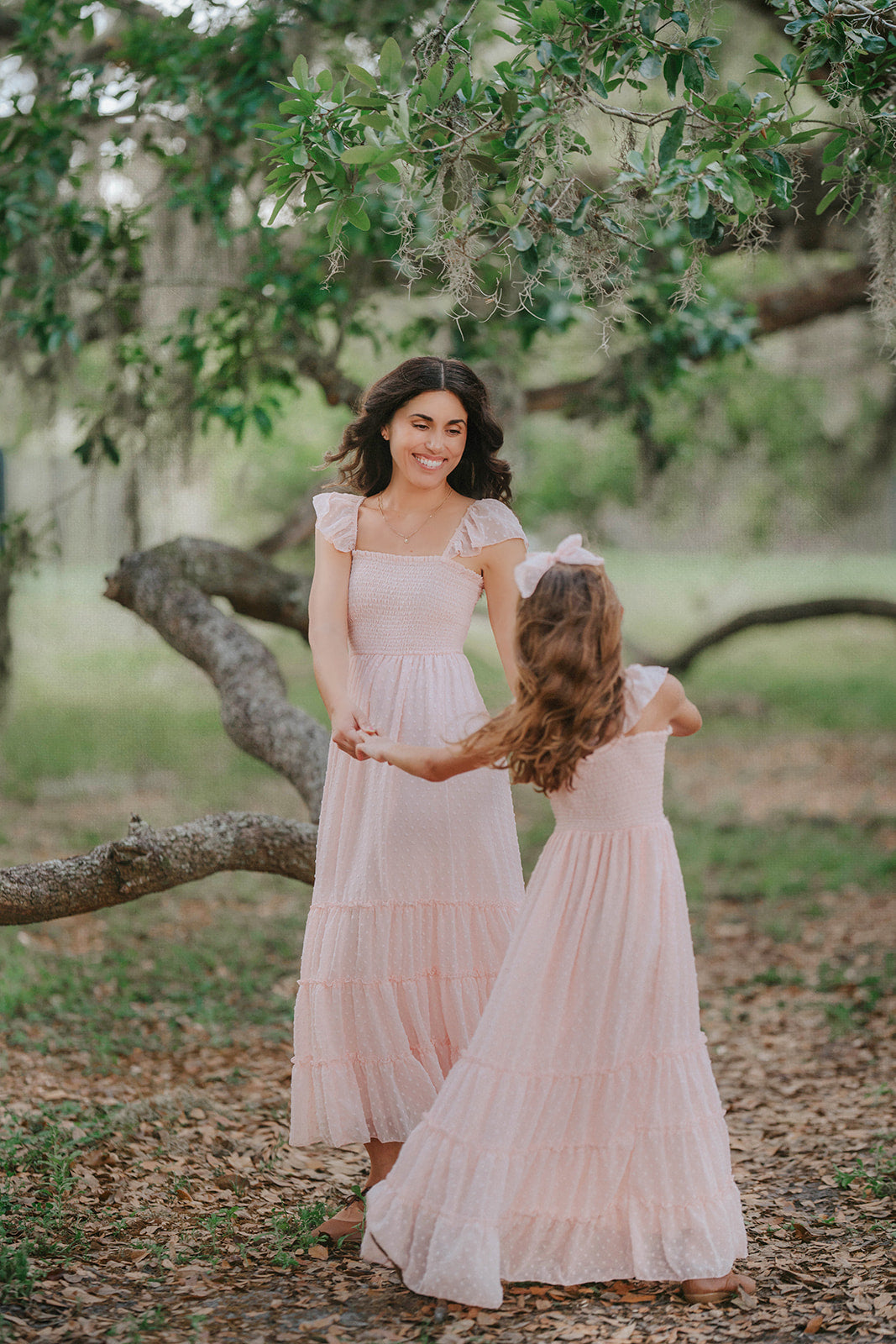 Matching Wild Strawberry Swiss dot dresses for women and girls photographed in a storybook orchard setting.