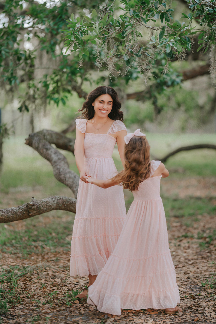 Matching Wild Strawberry Swiss dot dresses for women and girls photographed in a storybook orchard setting.