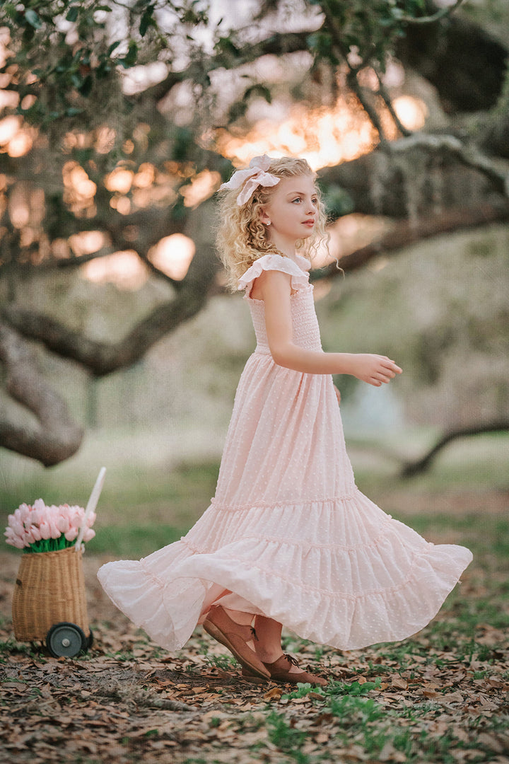 Girl spinning in Wild Strawberry Orchard Collection dress beneath oak trees