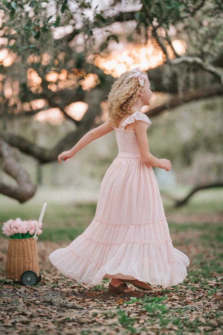 Girl walking in Wild Strawberry Swiss dot maxi dress with ruffle sleeves and full skirt