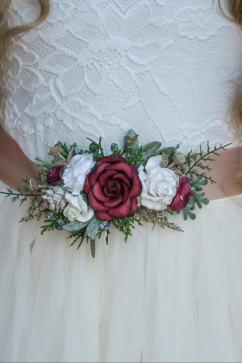 Floral sash with red, white, and green flowers on a white lace dress.